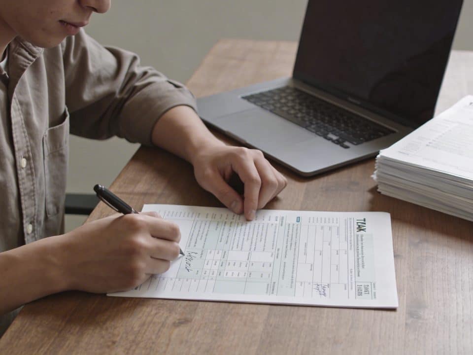 jeune adulte assis bureau remplissant formulaire fiscal