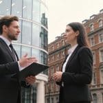 Deux agents immobiliers discutent devant deux immeubles différents