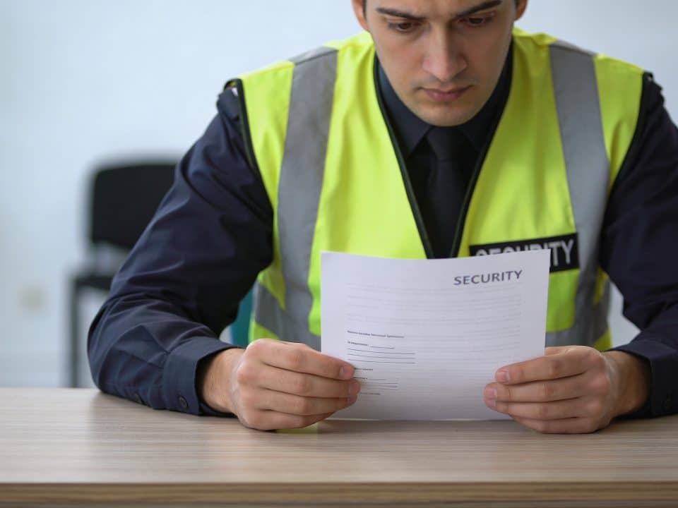employe en gilet de securite regardant contrat a moitie rempli sur un bureau