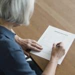 femme de 60 ans remplit un formulaire administratif