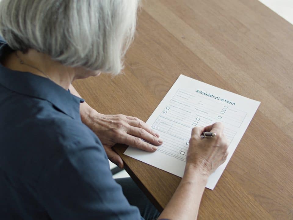 femme de 60 ans remplit un formulaire administratif