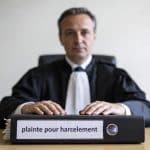 Huissier assis devant dossier epais, plainte pour harcelement