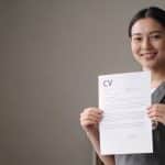Jeune aide soignante souriante tenant un CV