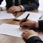 Dirigeants assis autour de table signant contrat