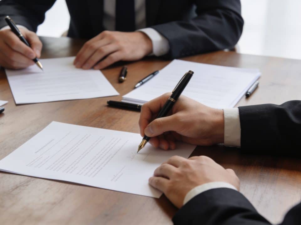 Dirigeants assis autour de table signant contrat