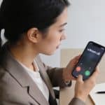 femme assise au bureau regardant smartphone affichant appel inconnu