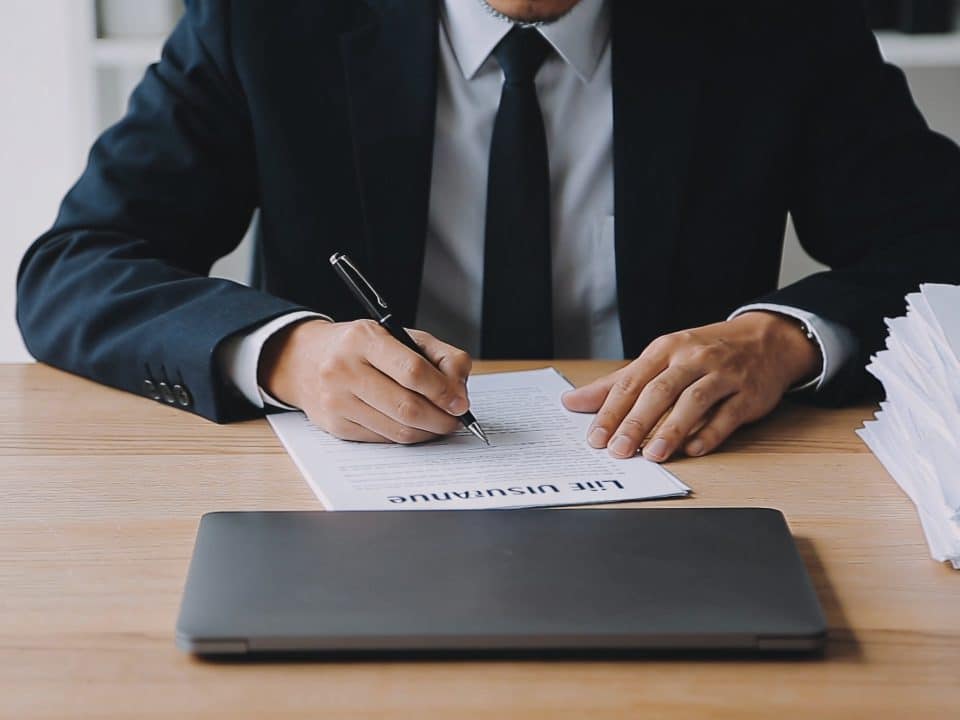 homme assis bureau signant documents assurance vie