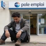 homme assis par terre devant bureau de pole emploi