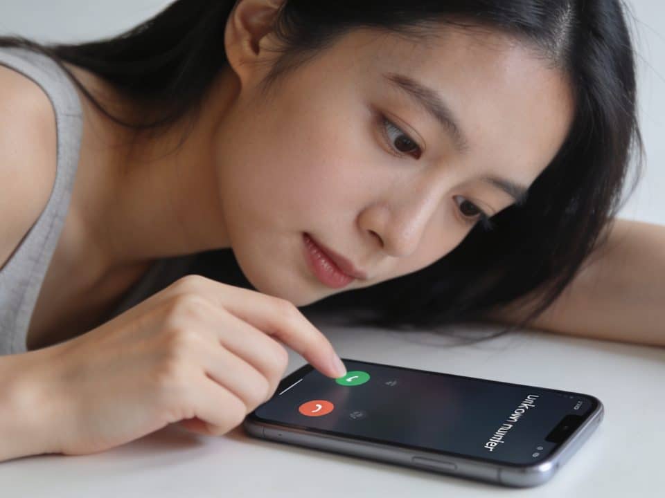 Jeune femme penchee sur smartphone affichant numero inconnu