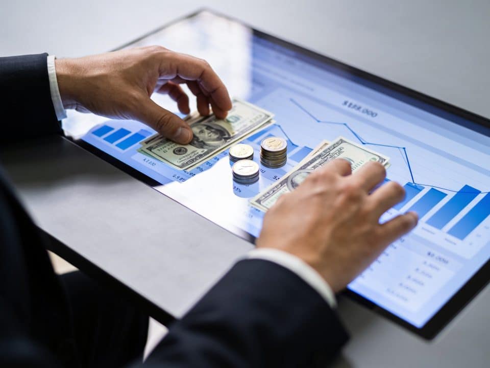 main posant des pieces devant ecran graphique banque