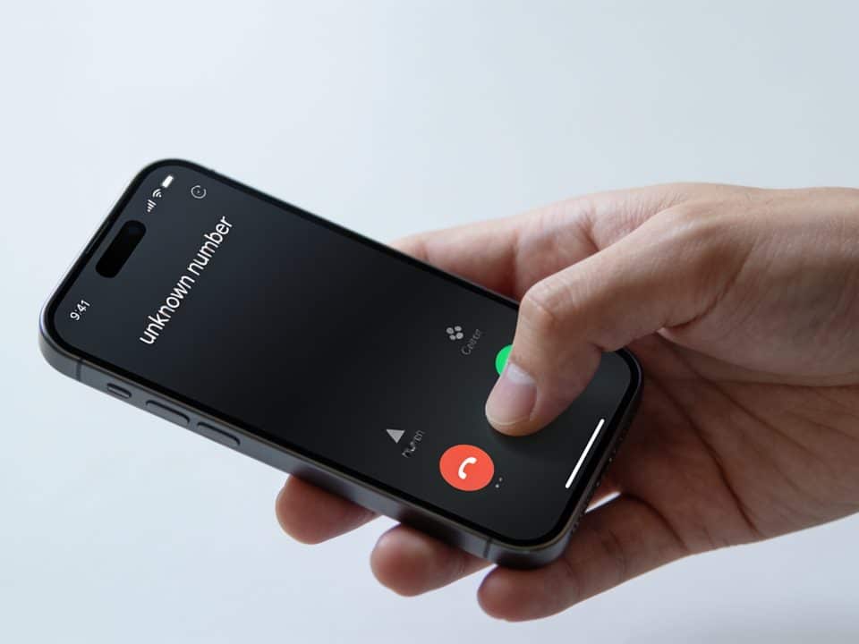 main tenant un smartphone affichant un numero inconnu