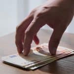mains offrant discrètement des billets sur une table