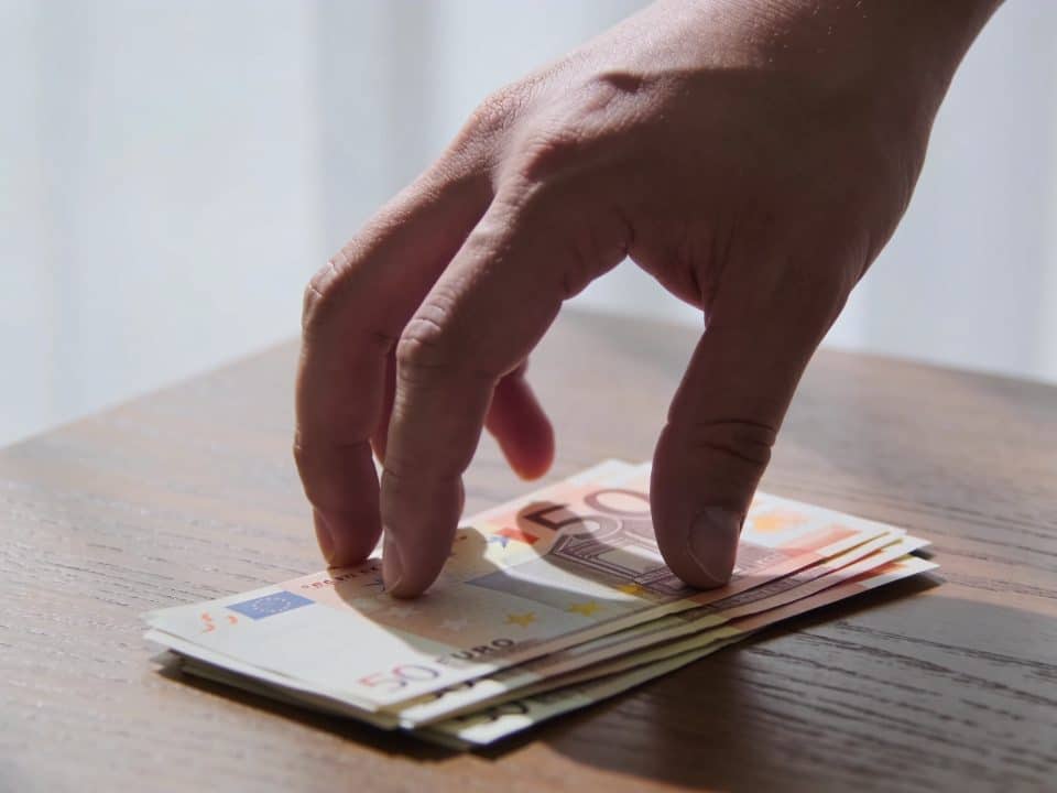 mains offrant discrètement des billets sur une table