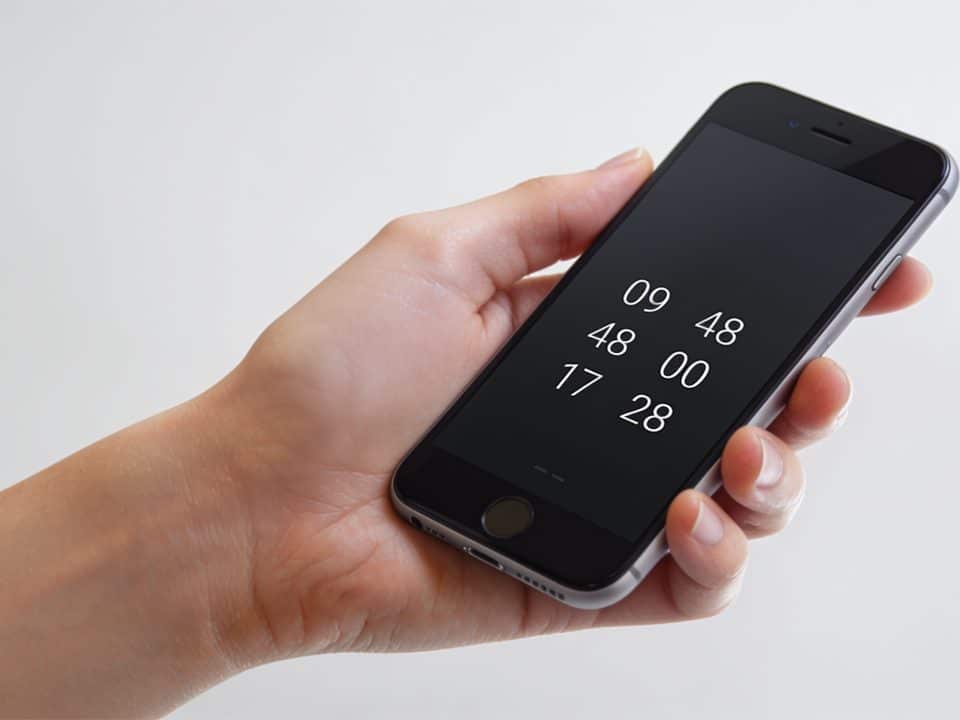 main tenant un smartphone affichant le numero 09 48 00 17 28