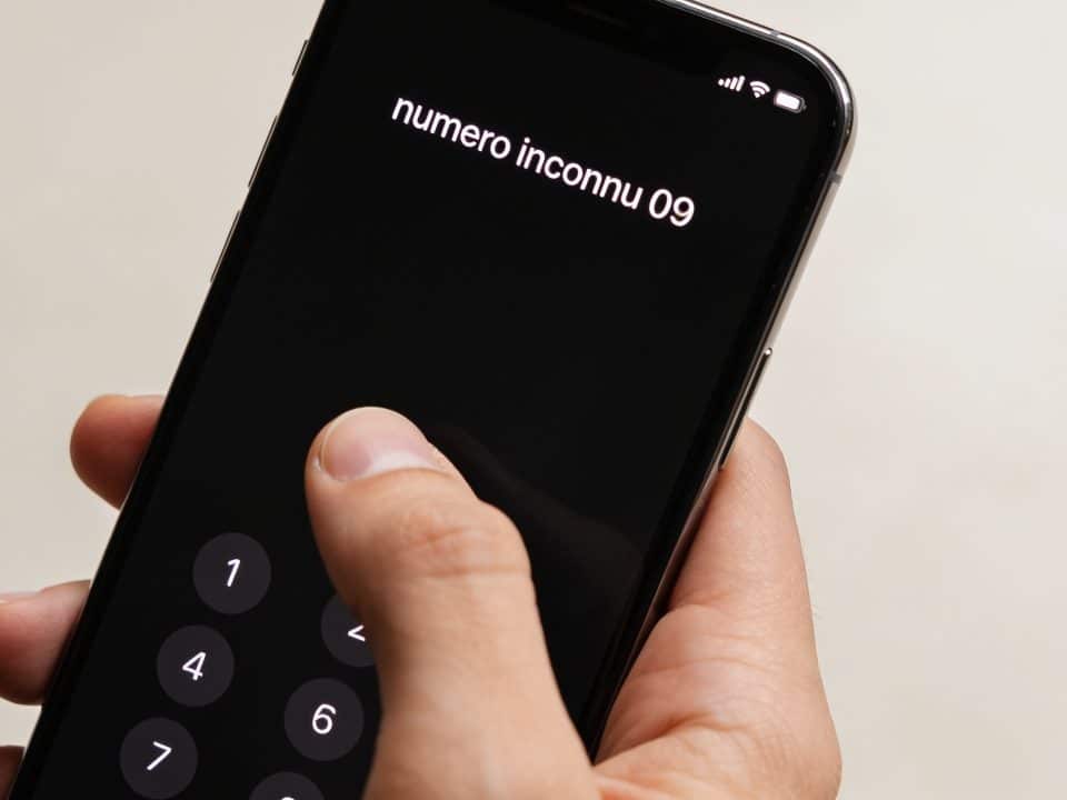 smartphone en main affichant numero inconnu 09